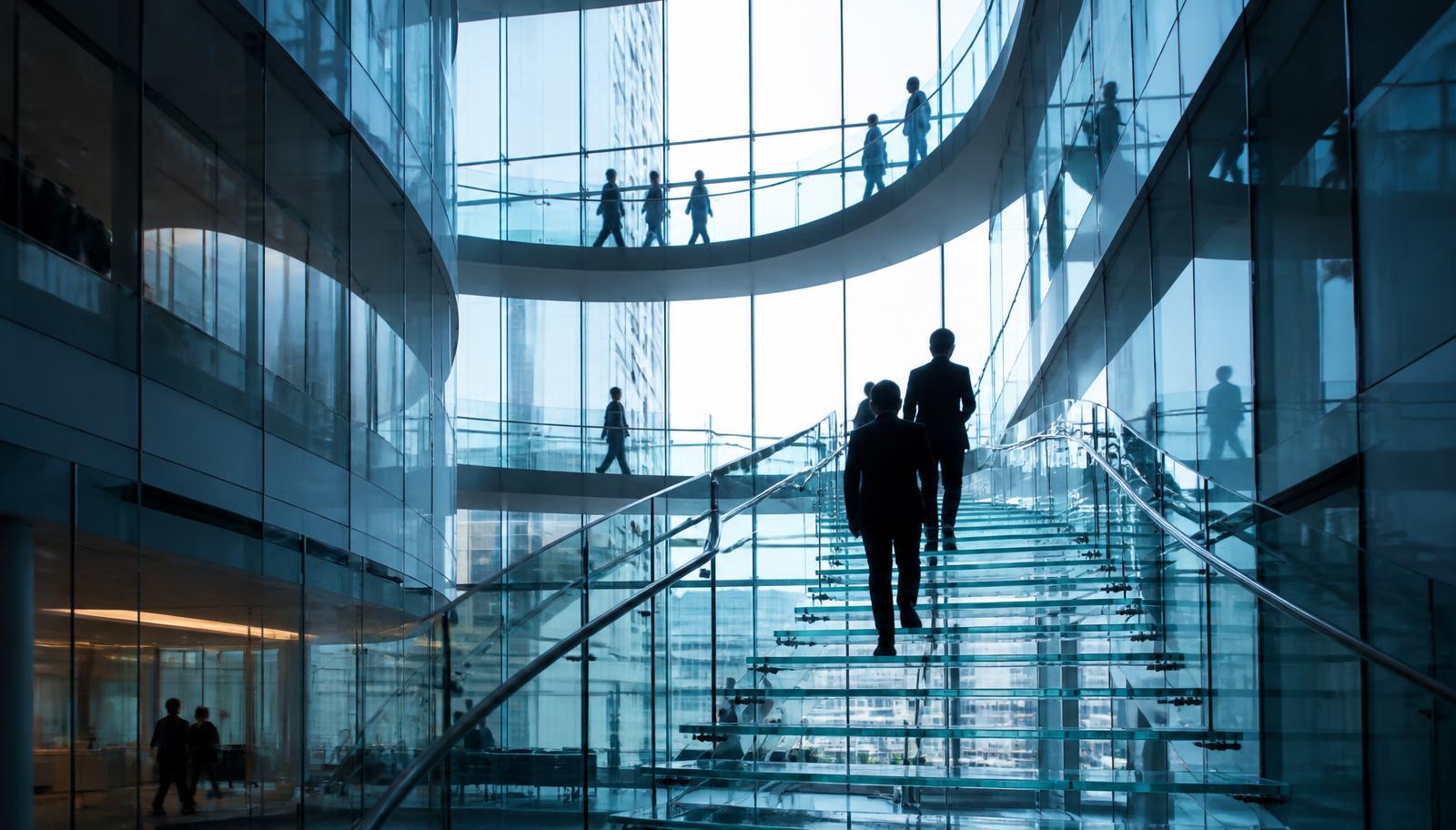Business professionals walking a glass staircase inside a modern corporate atrium